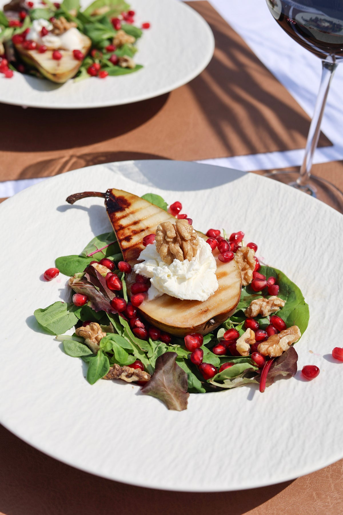Pera a la plancha caliente sobre una cama de lechuga, con cremoso mascarpone, crujientes nueces y frescas semillas de granada.