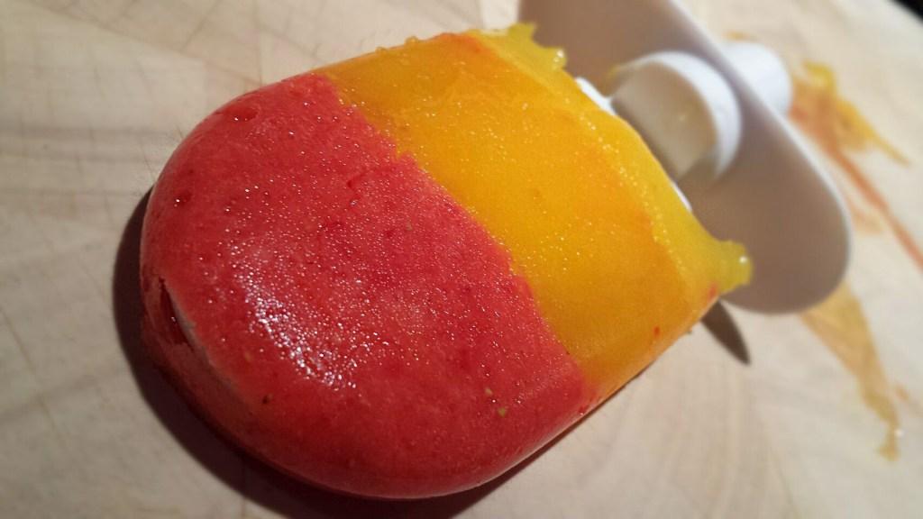 Healthy and colorful homemade rocket pop with strawberry, mango and orange
